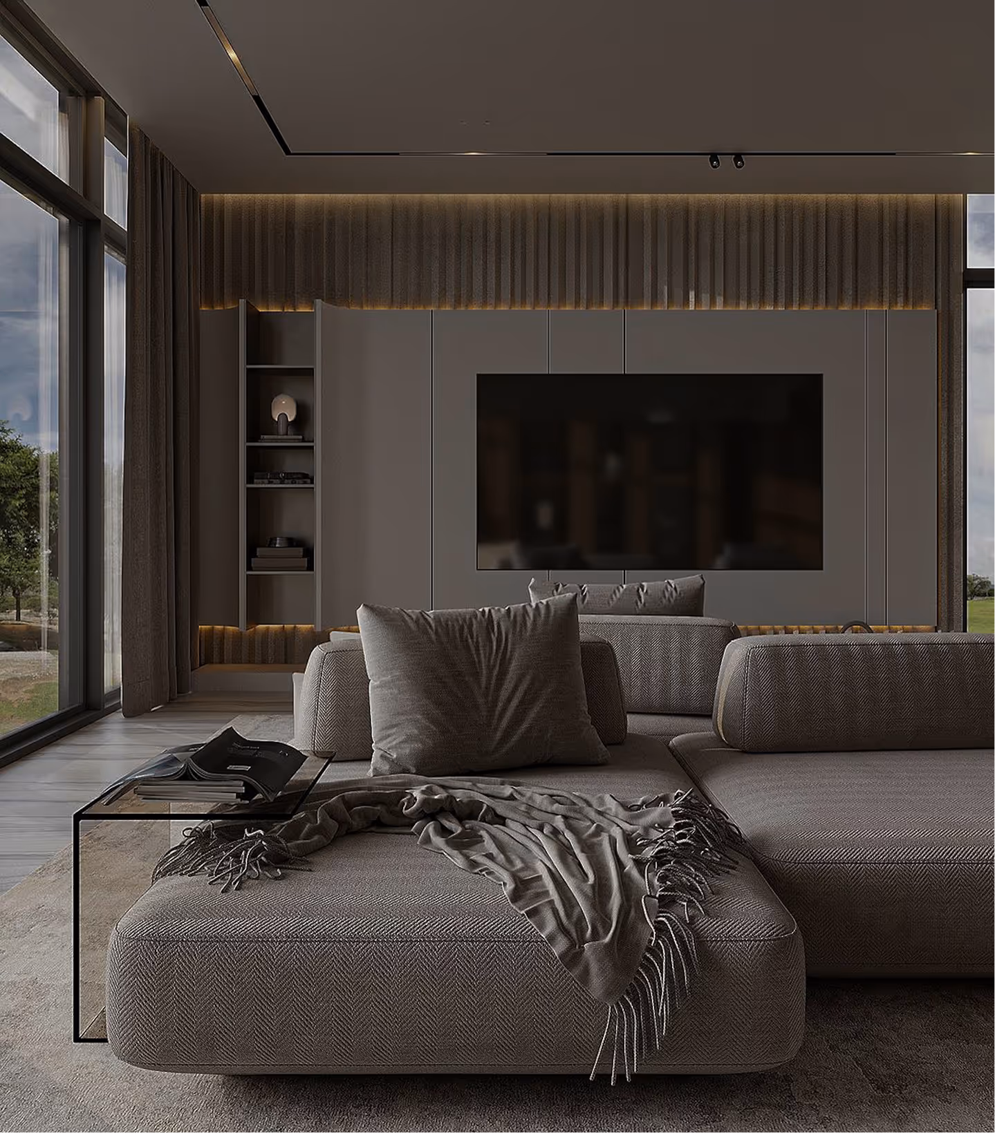 Modern living room with a large gray sectional sofa, textured throw blanket, glass side table, and wall-mounted flat-screen TV.